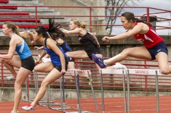 Freshman Charlene Manning (center) takes flight in the women’s 100-meter hurdles at the Cougar Open. Manning placed second in the event, finishing with a time of 16.11.