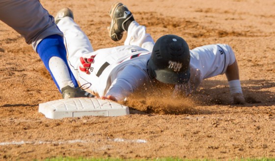 Sophomore Cole Hamilton slides back into first base after a pick-off attempt during the Saints’ 4-2 loss on Monday.