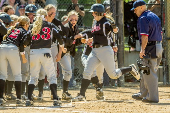The team waits for freshman catcher Mercedes Green as she crosses home plate after hitting a three-run home run in the fourth inning that gave the Saints a 3-2 lead and would ultimately give them a 4-2 victory to win the NWAACC championship.  Above right: The team celebrates with sparkling cider after winning the championship. Below right: The players first react to the go-ahead home run.