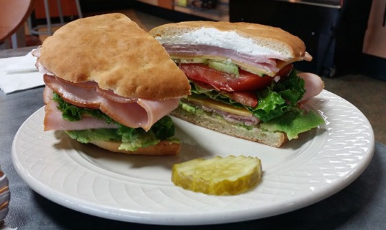 Above photo: “My Roomate’s Favorite,” a cold sandwich on gluten free flatbread with cream cheese in the middle, along with tomatoes, lettuce, and ham. Inset: interior of Liberated Bakery, a gluten-free bakery at 2518 S.E. Burnside Road in Gresham.