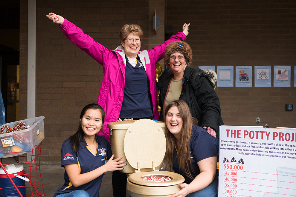 Rho Theta members, posing with their Potty Project 'golden throne'. Clockwise from bottom left: Officer May Tike; Advisor Beth Sammons; Alumna/former Officer Sule Whitlock; Officer Danielle Whitlock.