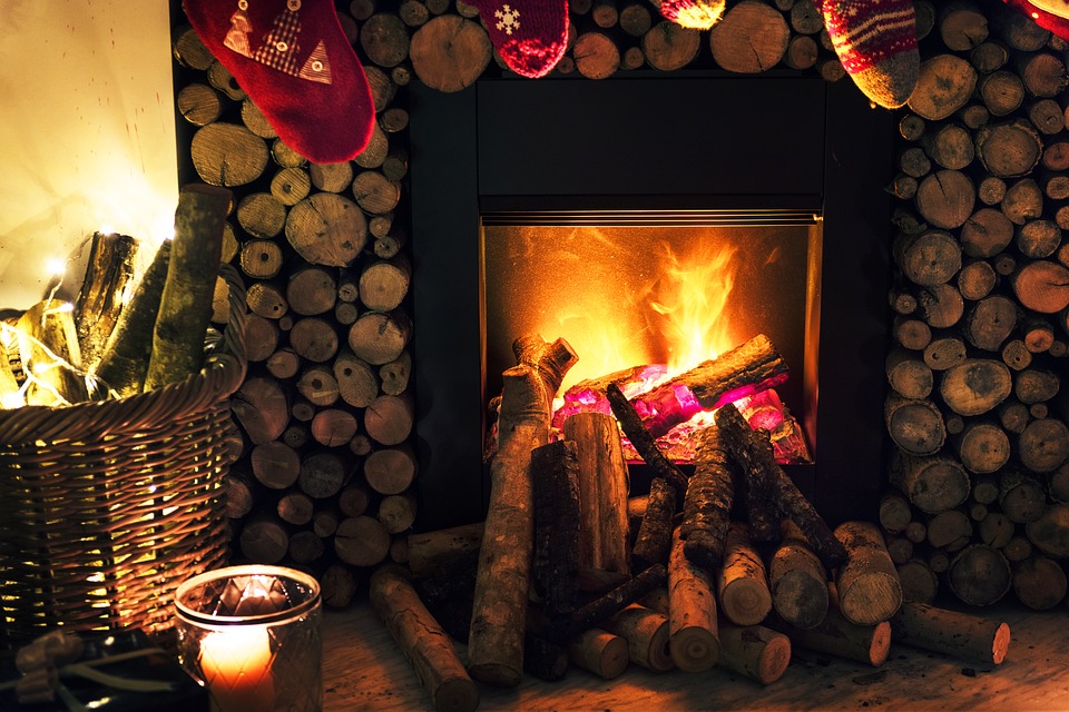 A photo of a fireplace with candles lit and stockings hung.