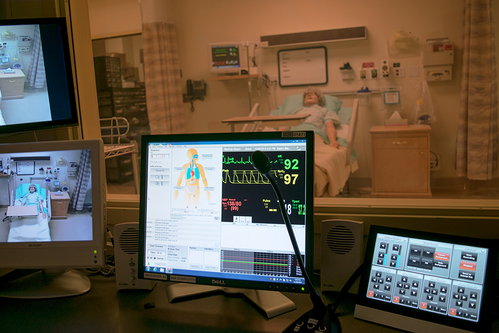 Nursing simulation in progress, monitors and the real-life mannequin 'patient.'