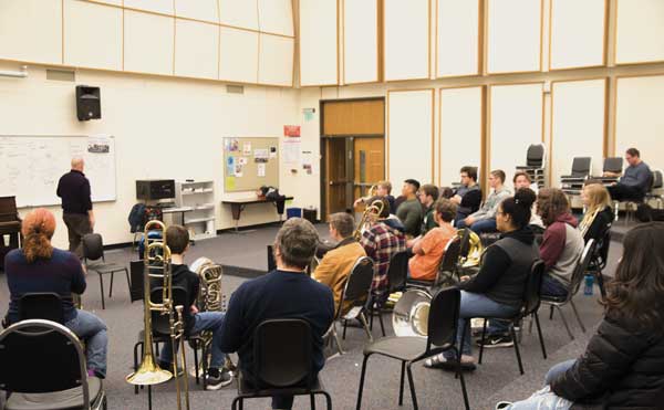 Participants listen to Patrick Sheridan with their brass instruments to learn more about breathing techniques.