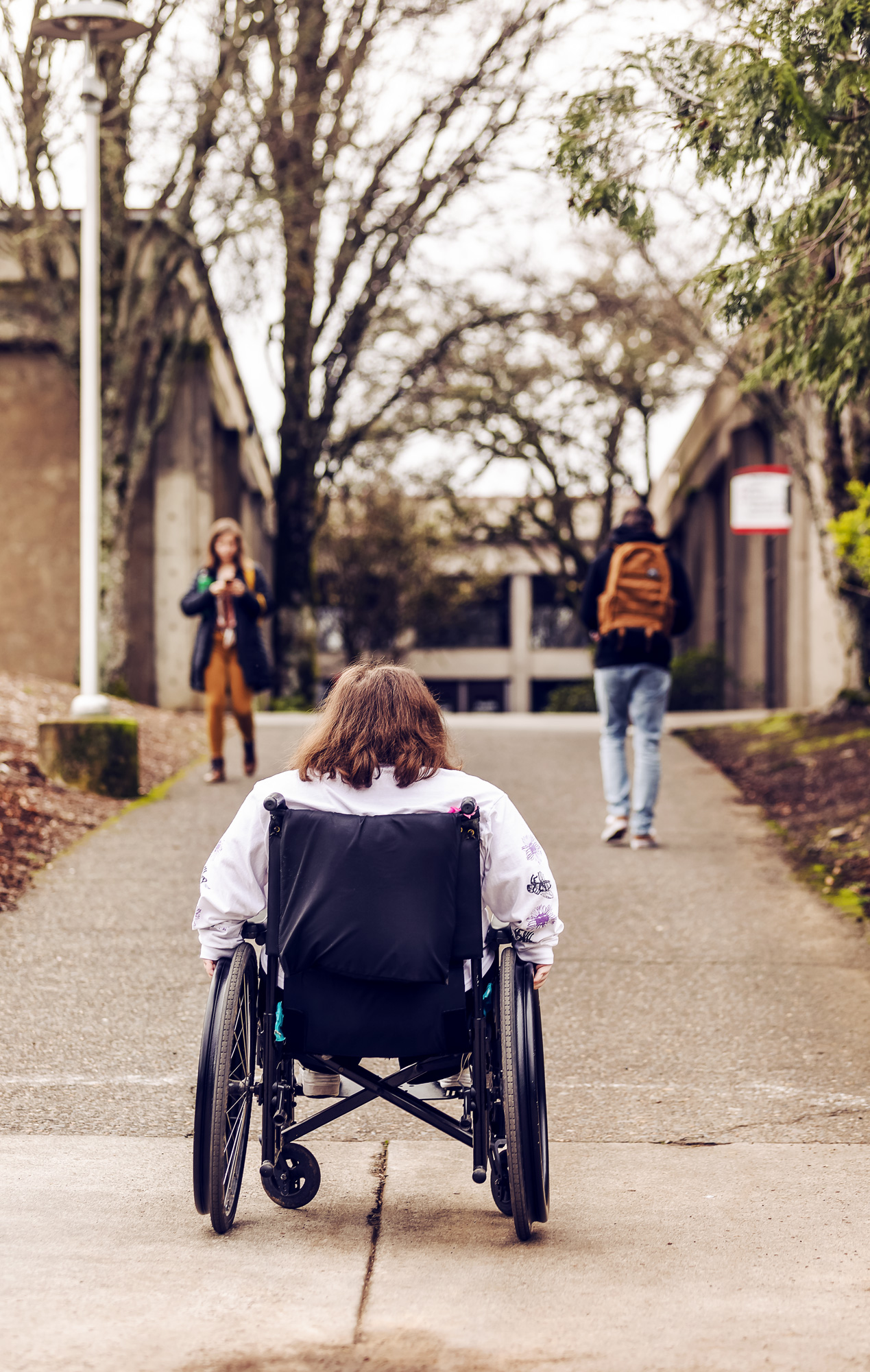 Photo capturing someone in a wheelchair looking up a steep hill to show accessibility issues on the campus.