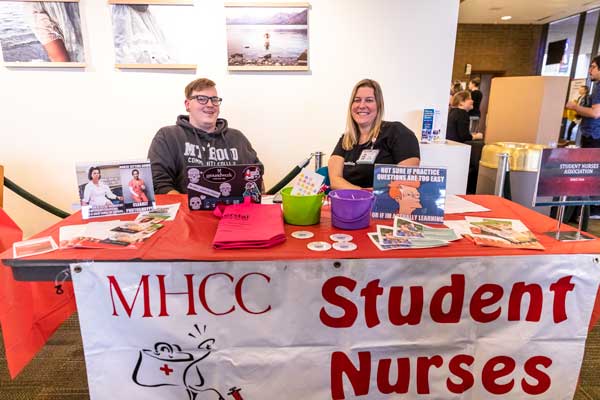 Photo of a man and woman sitting with their table for the Student Nurses Association.