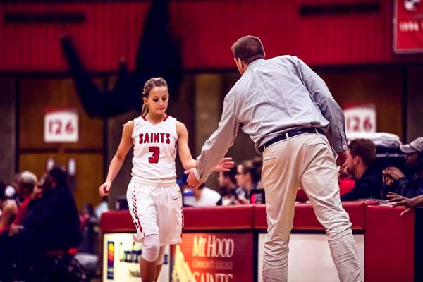 Photo capturing Saints woman player #3, Kassidy Ellett, shaking hands with Coach Vandenboer.