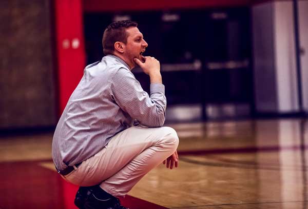 Photo of Coach Vandenboer crouching as he watched his team in action.