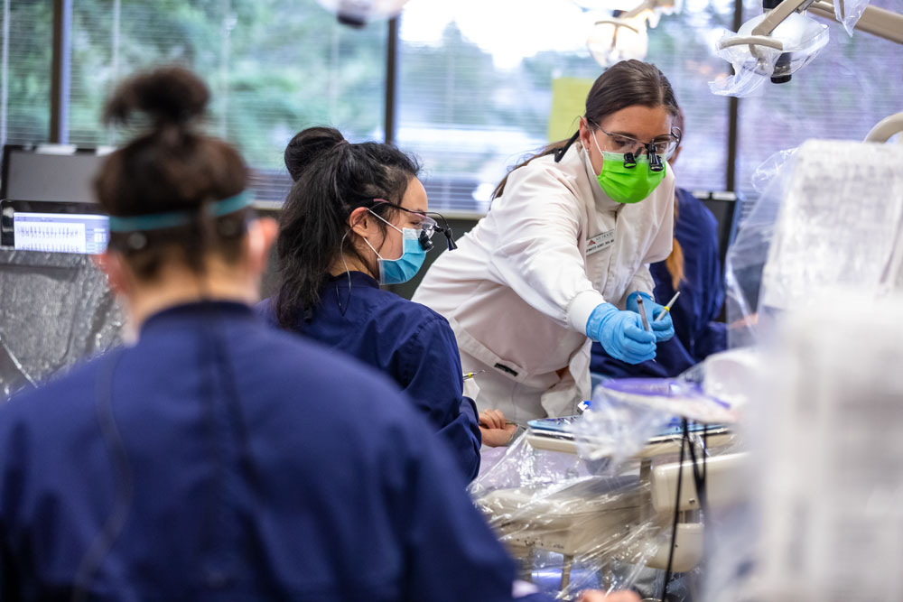 Photograph of MHCC dental hygiene instructor working in the lab with multiple students.