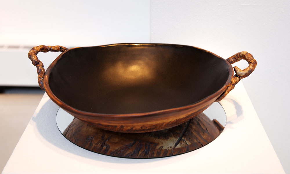 Photograph of a wide and shallow bowl, resting on a mirror to show the leaf patterns on the outside.