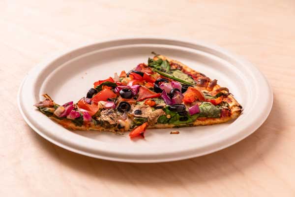 Photograph of a $2.00 supreme pizza slice on a brown paper plate from the campus cafeteria.