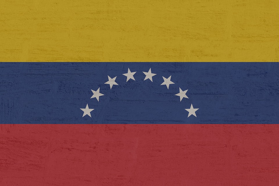 Venezuela's flag, a yellow horizontal stripe at the top, followed by blue and red with a half circle of white stars in the middle blue stripe.