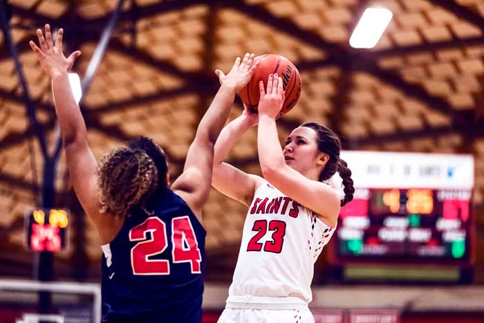 Saints women's basketball player Courtney Jackson shooting the ball against Clackamas Cougars player, Landy Williams.