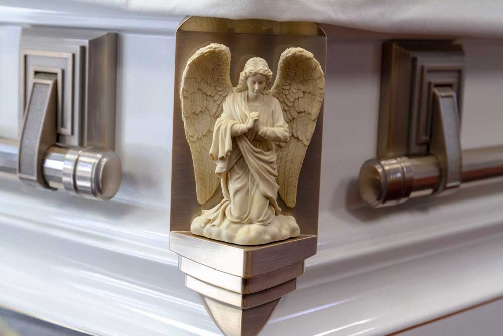 A close up image of a casket corner with an angel detailing on the outside.