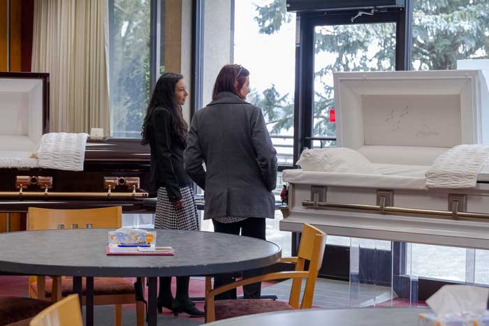 Two people talking next to caskets on display.
