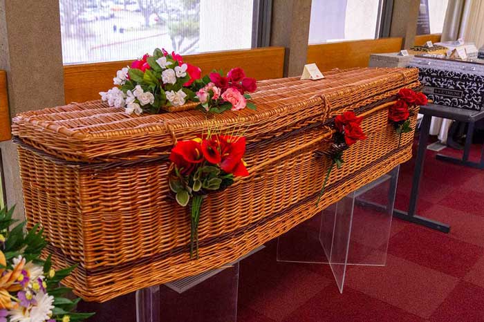 A woven casket made out of wood decorated with flowers.