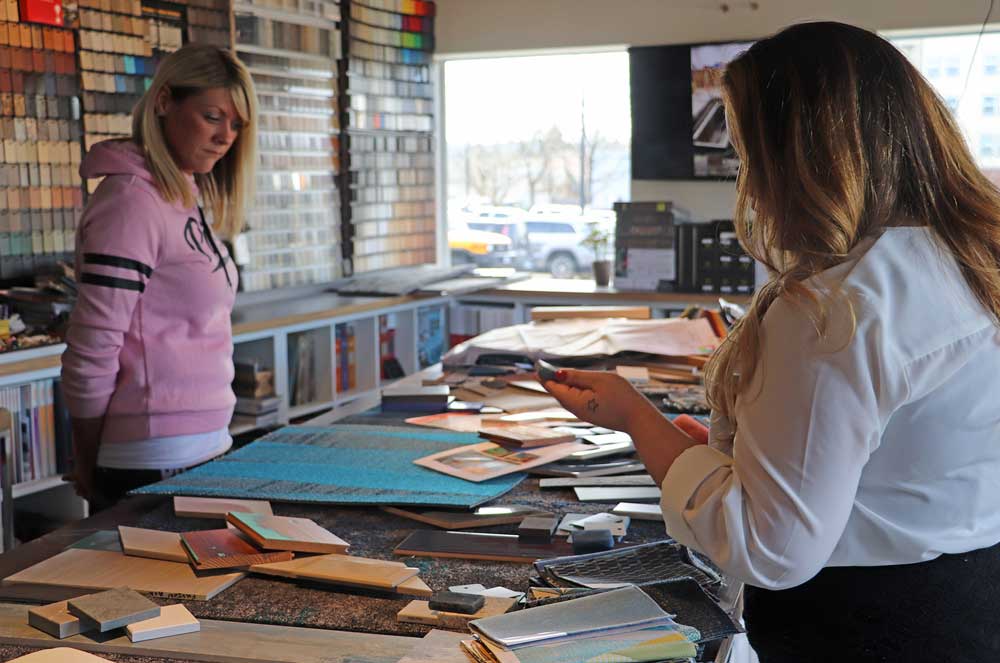 Two female students looking at design samples on a table top.