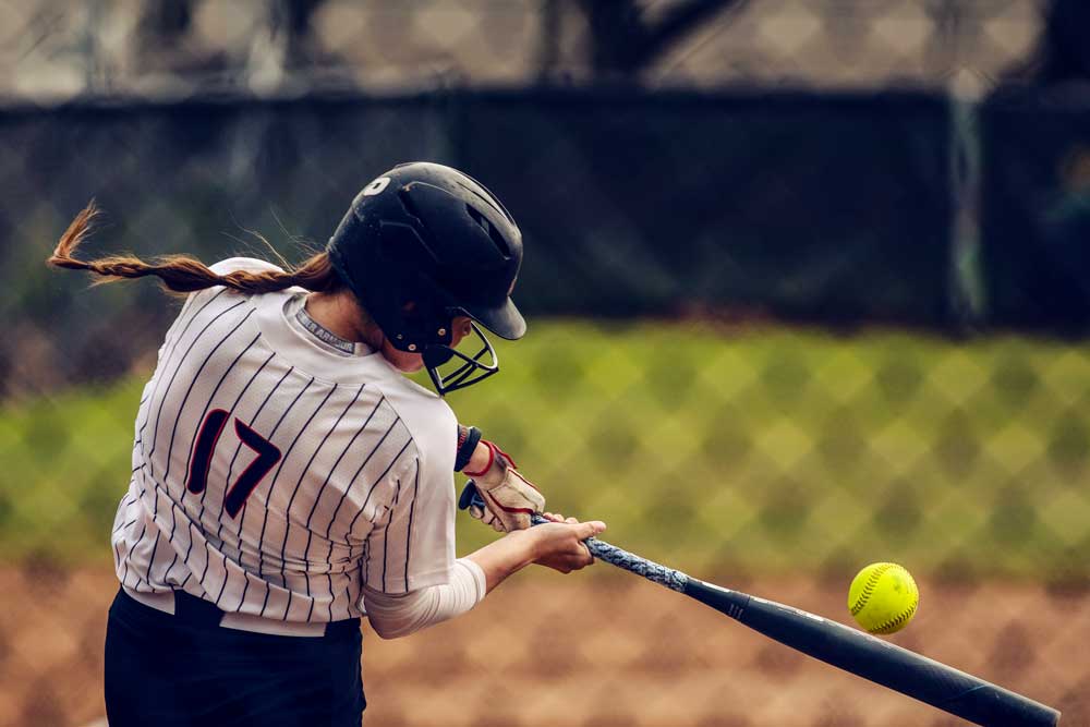 #17 Hitting the ball as seen from behind the fence.