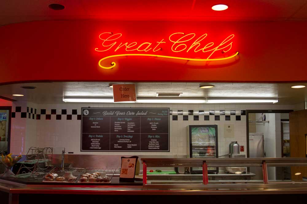 A view of the salad bar and neon sign stating "great chefs"