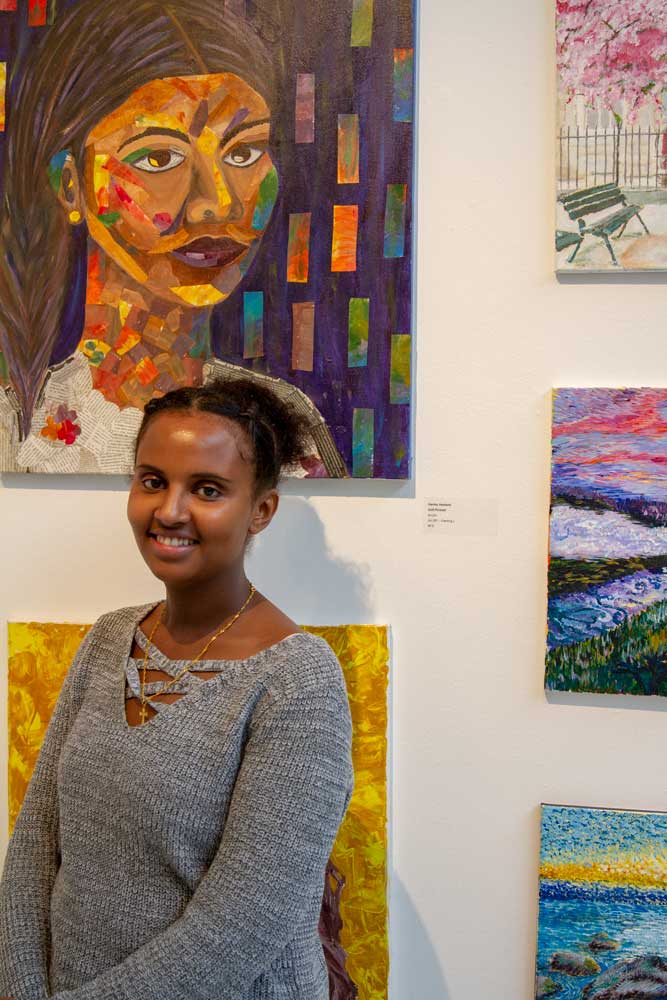 Ganitu Henbeto standing in front of her painting.