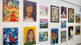 Various colorful paintings across Visual Arts Gallery wall